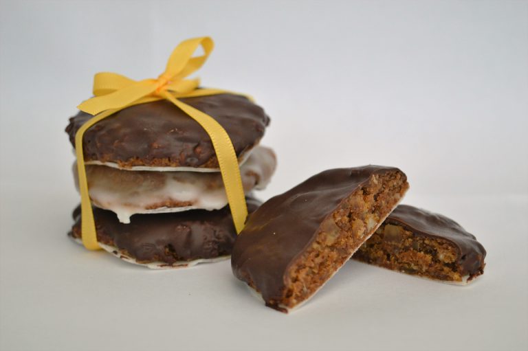 Authentic Elisen-Lebkuchen covered in chocolate and icing stacked on top of each other. Tied together with a yellow ribbon.